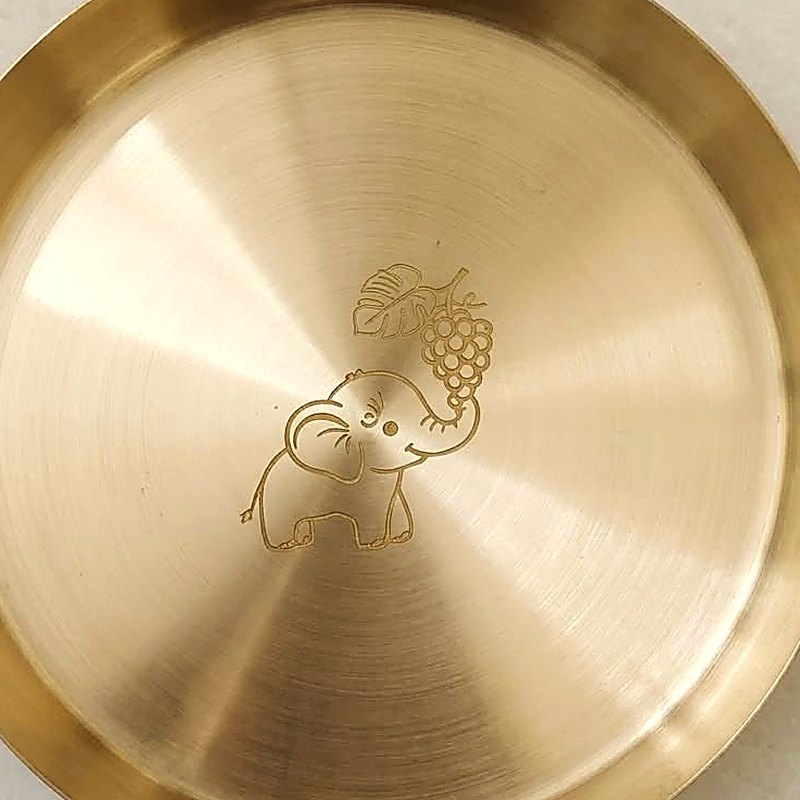 Close-up of the elephant and grape-leaf motif engraved on the bronze thali plate
